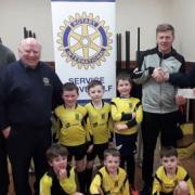 Former President of the Hunterston Rotary Club, Ewan Cochran (right) and fellow Rotarian Jim Jackson (second from the left) presents the Community Award to representatives of the West Kilbride Deltas football team.