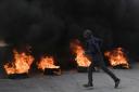 A masked Palestinian demonstrator burns tyres in a protest against a deadly Israeli army raid at Aida Refugee camp, in the West Bank city of Bethlehem