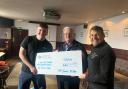 Jim and Devon accept the cheque from Jim Miller