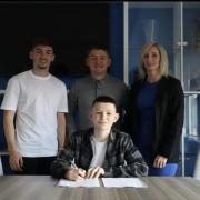 Harvey poses with his proud family as he signs his deal. Pic credit: Harvey Gilmour