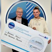 Brooke Neely accepting her donation from Cunninghame Housing Association chairperson Lesley Keenan.